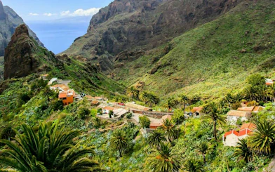 Masca Village nestled in lush green mountains, Tenerife, with palm trees and scenic views.