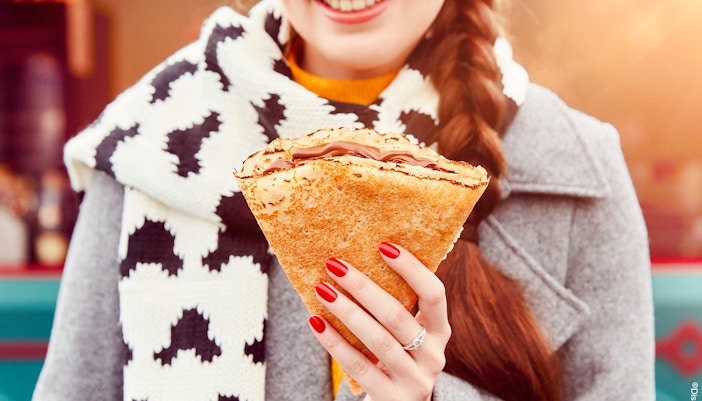 Person enjoying a crepe at Disneyland Paris during Christmas 2025.