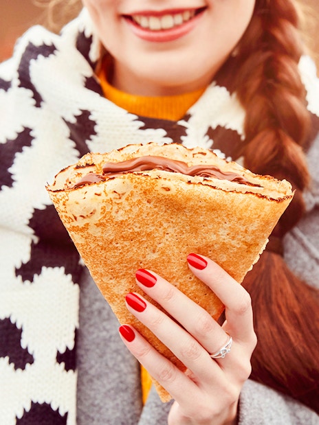 Person enjoying a crepe at Disneyland Paris during Christmas 2025.
