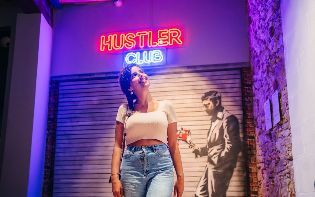 Tourist smiling at Banksy artwork in Barcelona museum.