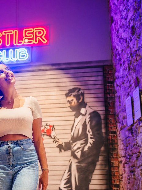 Tourist smiling at Banksy artwork in Barcelona museum.