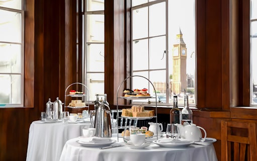 Afternoon tea setup with sandwiches and pastries, view of Big Ben from London Eye.