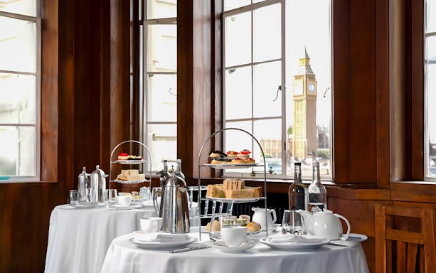 Afternoon tea setup with sandwiches and pastries, view of Big Ben from London Eye.