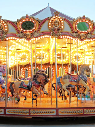 Carousel with illuminated horses at a theme park during evening.