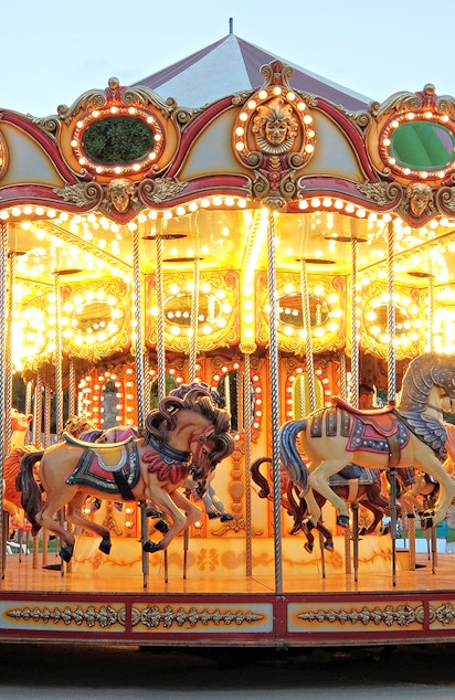 Carousel with illuminated horses at a theme park during evening.
