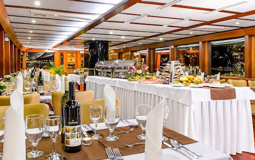 Cruise dining room with elegantly set tables and buffet spread.