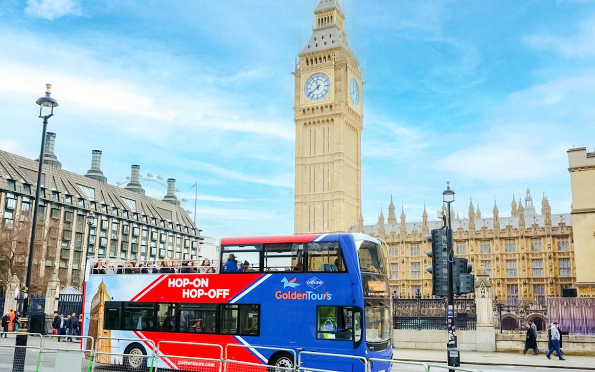 Golden Tours Hop-on Hop-off bus near Big Ben and Houses of Parliament, London.