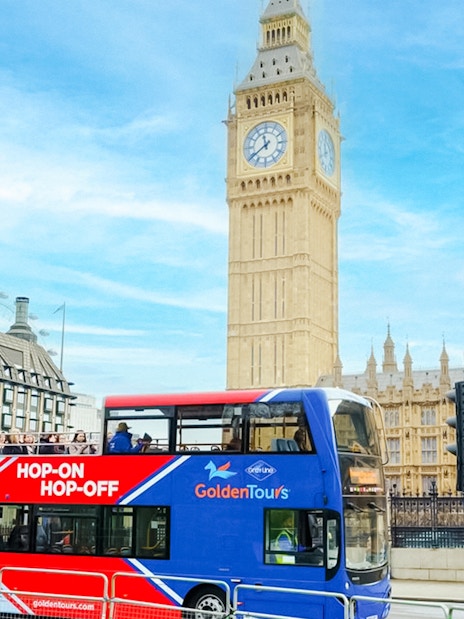 Golden Tours Hop-on Hop-off bus near Big Ben and Houses of Parliament, London.