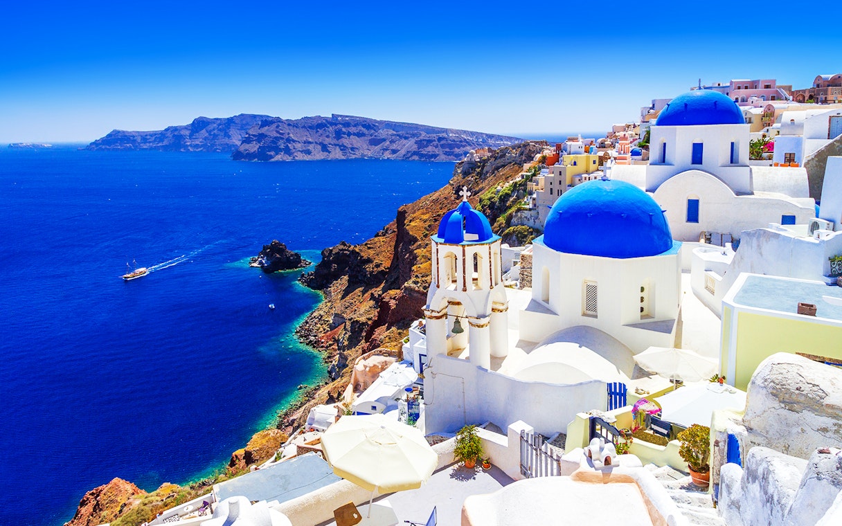Oia town on Santorini island with blue-domed churches and Aegean Sea view.