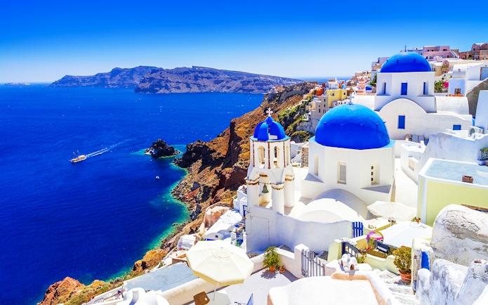 Oia town on Santorini island with blue-domed churches and Aegean Sea view.