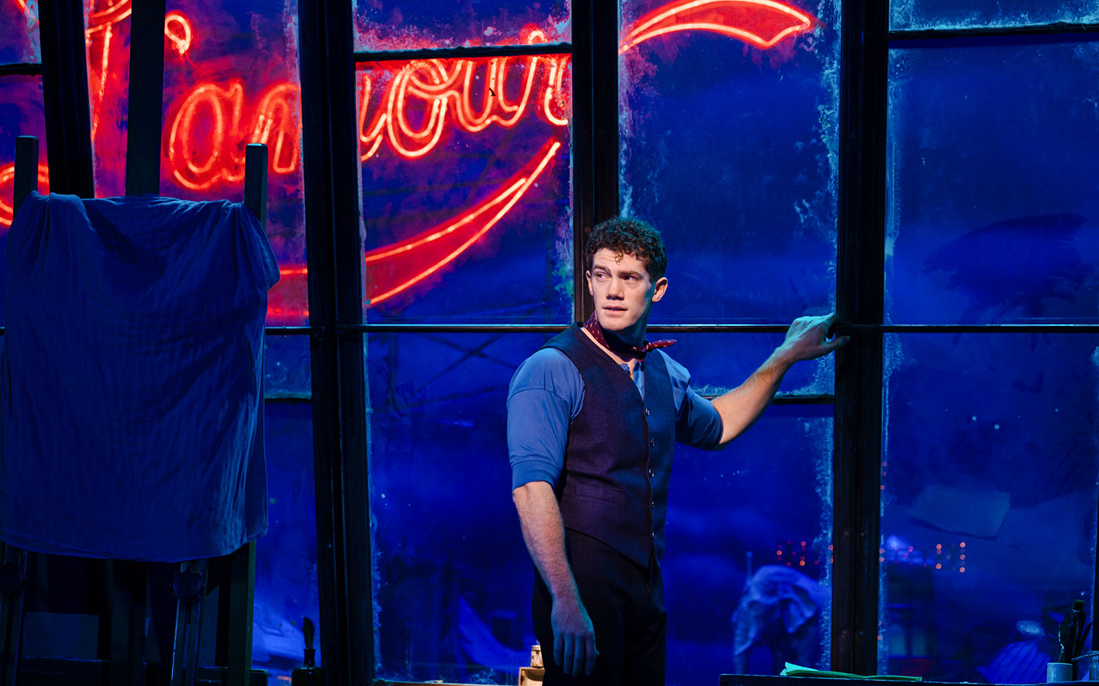 Performer on stage during Moulin Rouge! The Musical, West End, with neon sign backdrop.