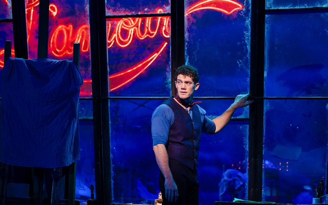 Performer on stage during Moulin Rouge! The Musical, West End, with neon sign backdrop.