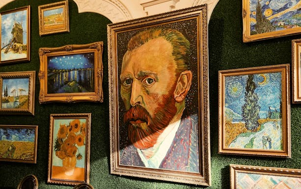 Van Gogh paintings including self-portrait and Starry Night displayed on a gallery wall.