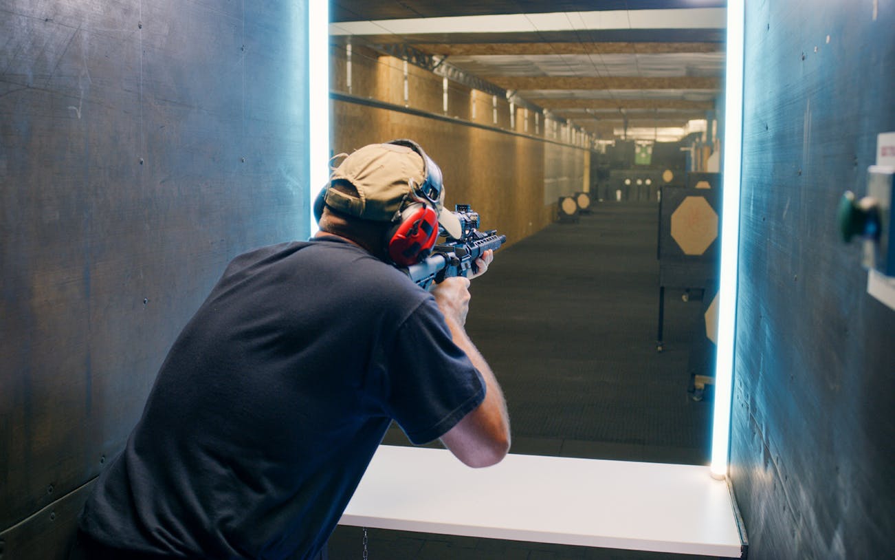 Person aiming rifle at targets in Warsaw shooting range.