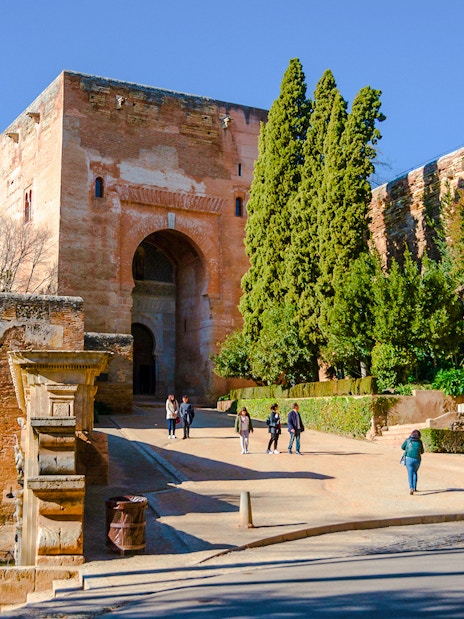 Gate of Justice at Alhambra, Granada, with visitors walking towards the entrance.