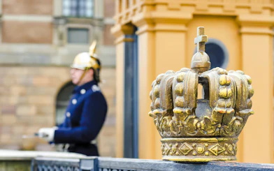 Golden crown detail with guard in uniform at Royal Palace, Stockholm.
