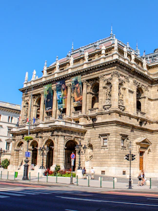 Facade of the Hungarian State Opera in Budapest with ornate architecture and street view.