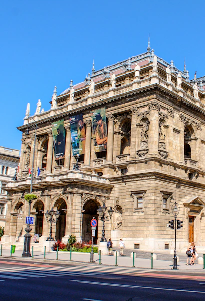 Facade of the Hungarian State Opera in Budapest with ornate architecture and street view.