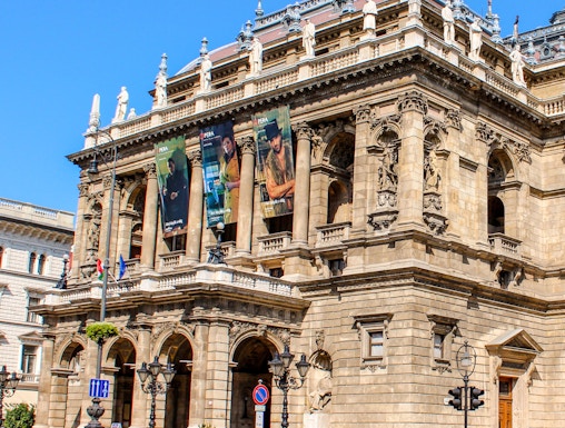 Facade of the Hungarian State Opera in Budapest with ornate architecture and street view.