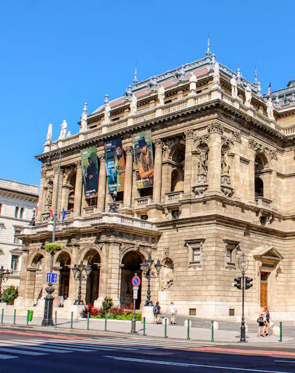 Facade of the Hungarian State Opera in Budapest with ornate architecture and street view.
