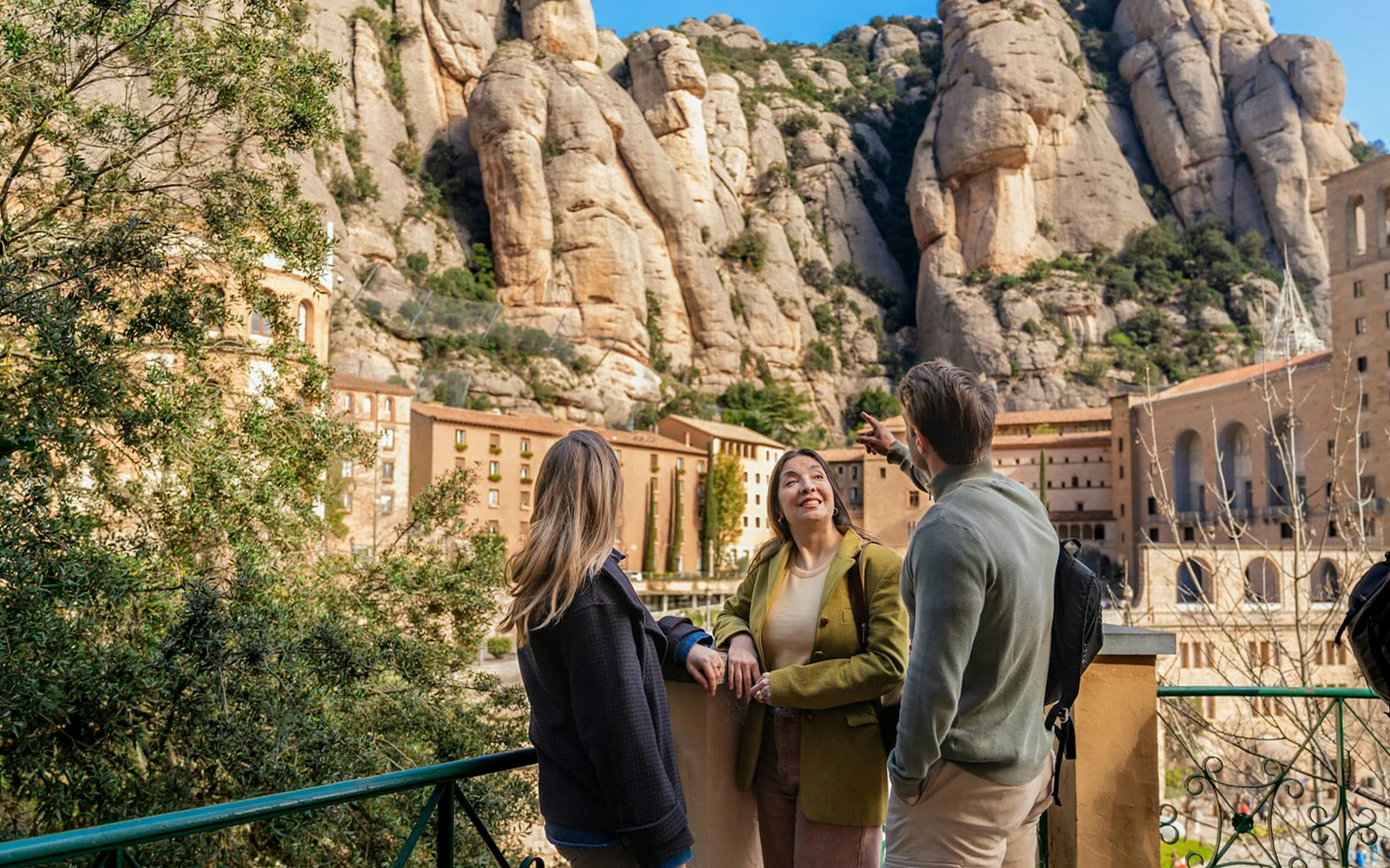 Tourists with guide at Montserrat mountain viewpoint, Spain, admiring rocky landscape.