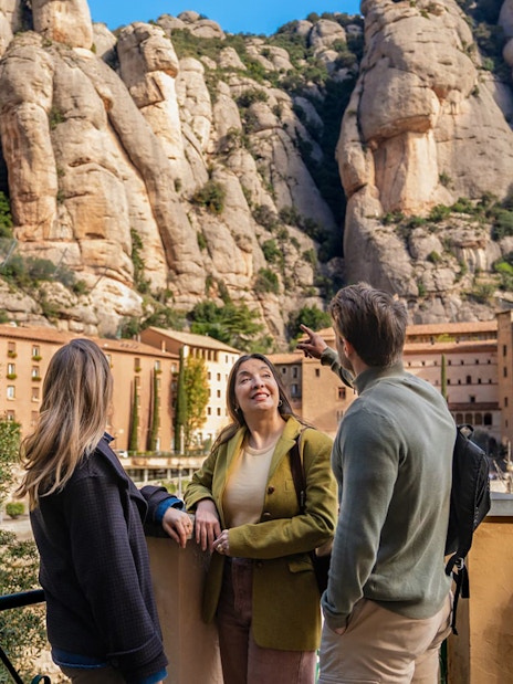 Tourists with guide at Montserrat mountain viewpoint, Spain, admiring rocky landscape.