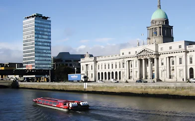 River cruise boat on the Liffey with Dublin's Custom House in the background.