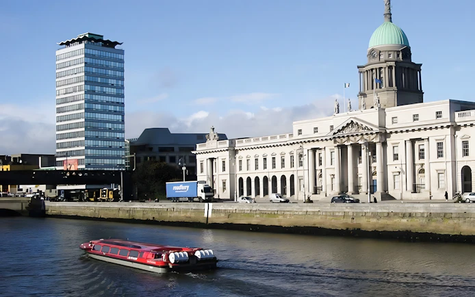 River cruise boat on the Liffey with Dublin's Custom House in the background.