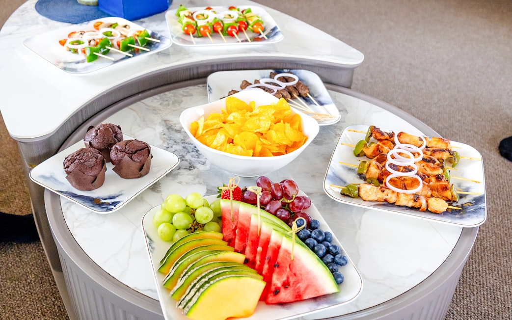 Fruits and snacks on a yacht table with skewers, chips, and muffins.