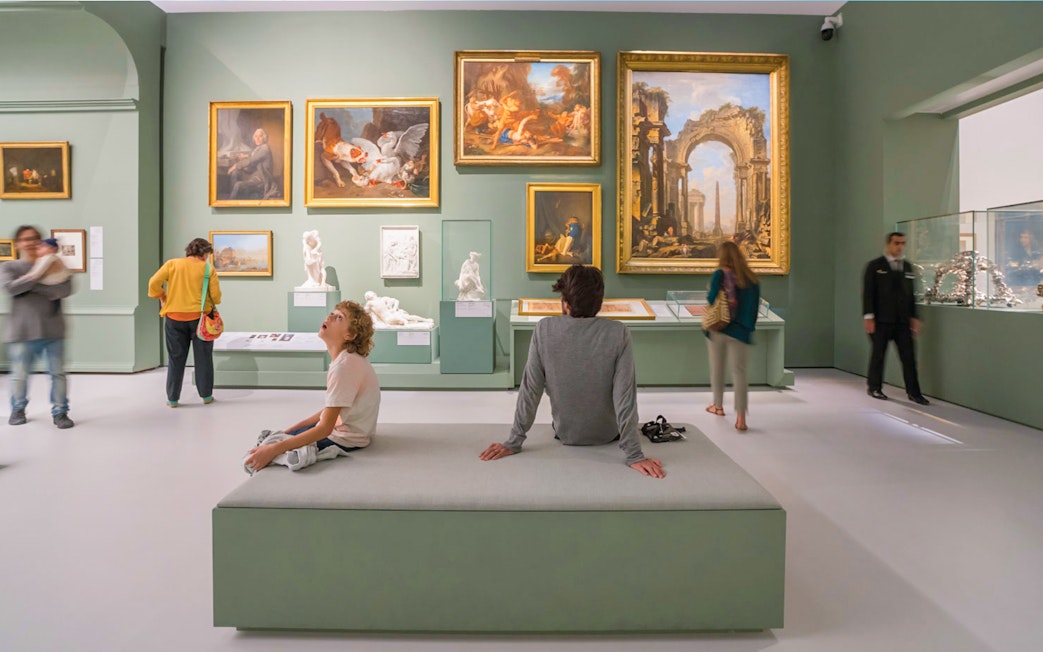 Tourists exploring art exhibits at the Louvre Museum Abu Dhabi.