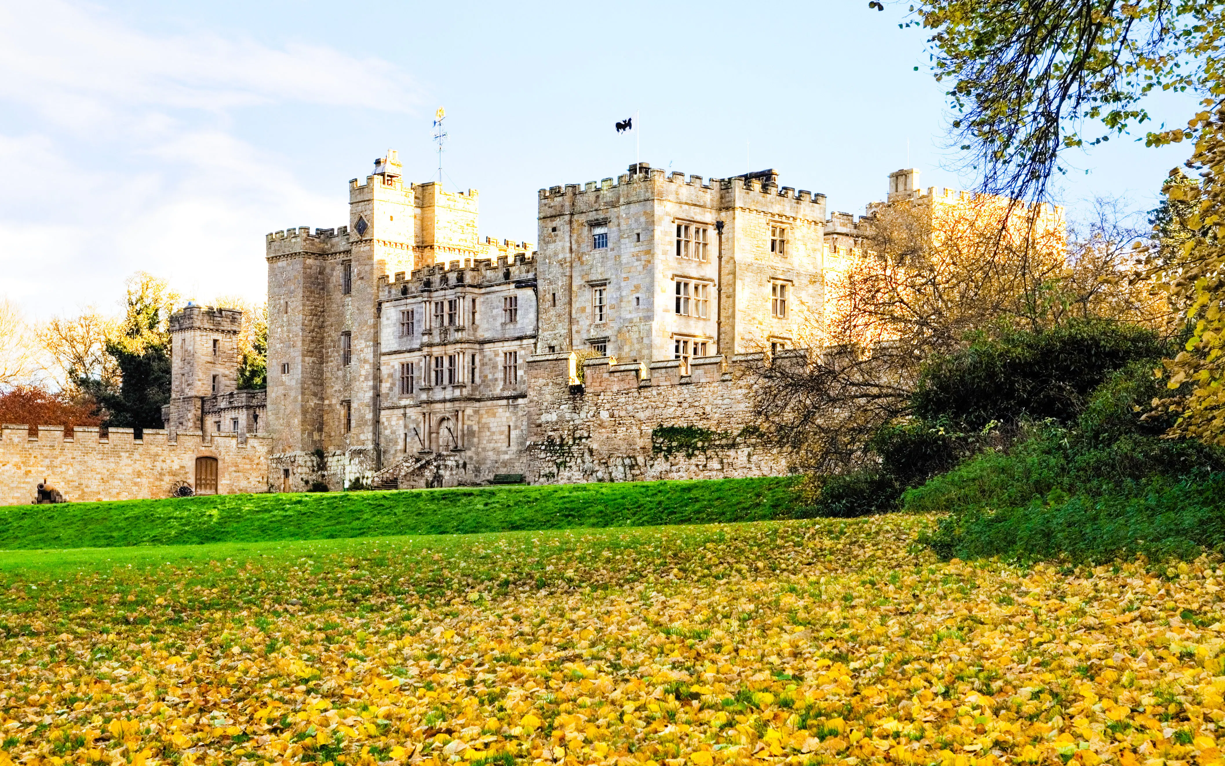 Alnwick Castle surrounded by autumn leaves and greenery.