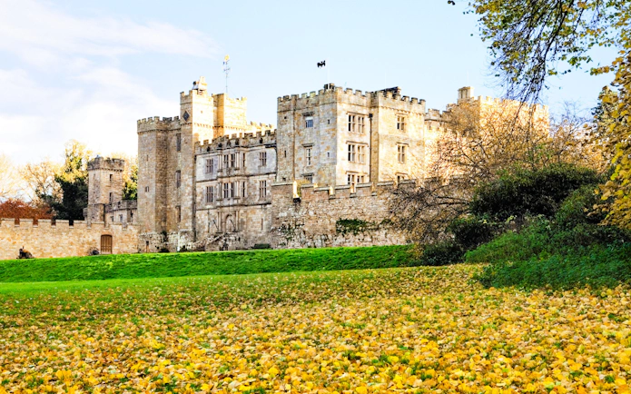 Alnwick Castle surrounded by autumn leaves and greenery.
