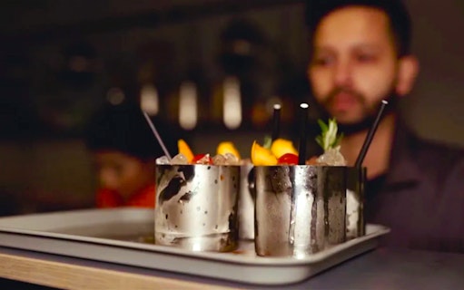 Cocktails served in metal cups at Alcotraz prison-themed bar.