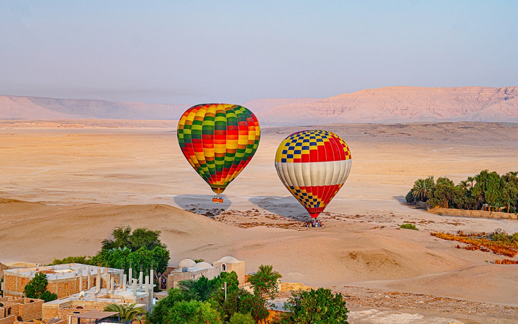 Hot air balloons over desert landscape in Luxor, Egypt.