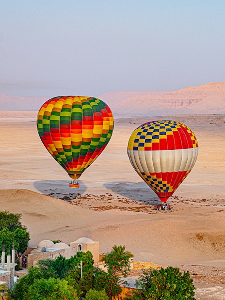 Hot air balloons over desert landscape in Luxor, Egypt.