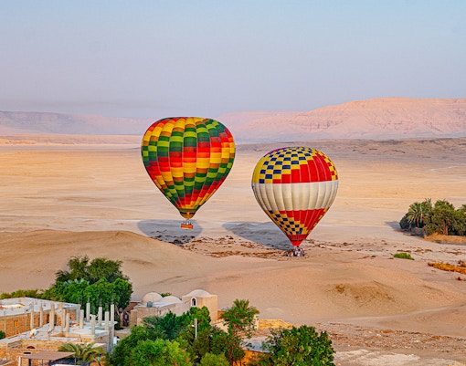 Hot air balloons over desert landscape in Luxor, Egypt.