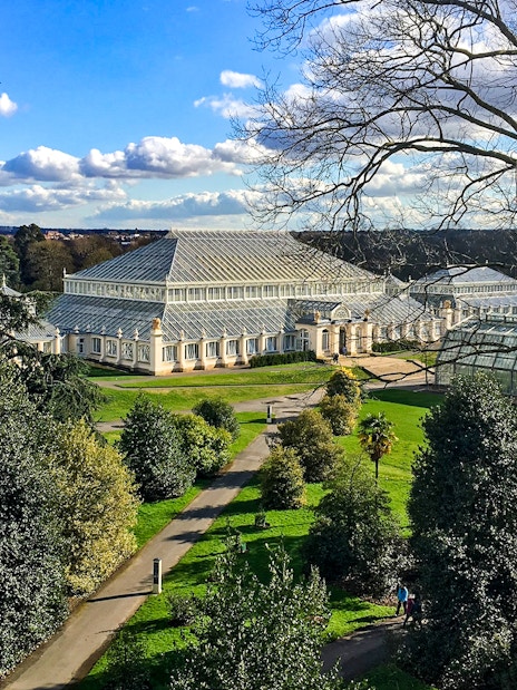 Kew Gardens glasshouse surrounded by trees and pathways, London.