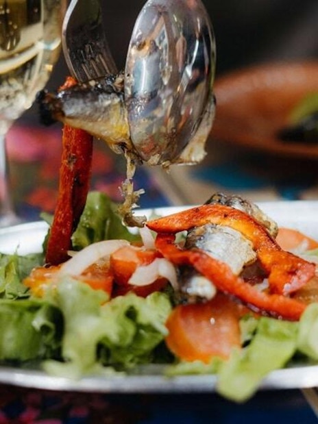 Grilled sardines with peppers and salad on a Lisbon food tour plate.