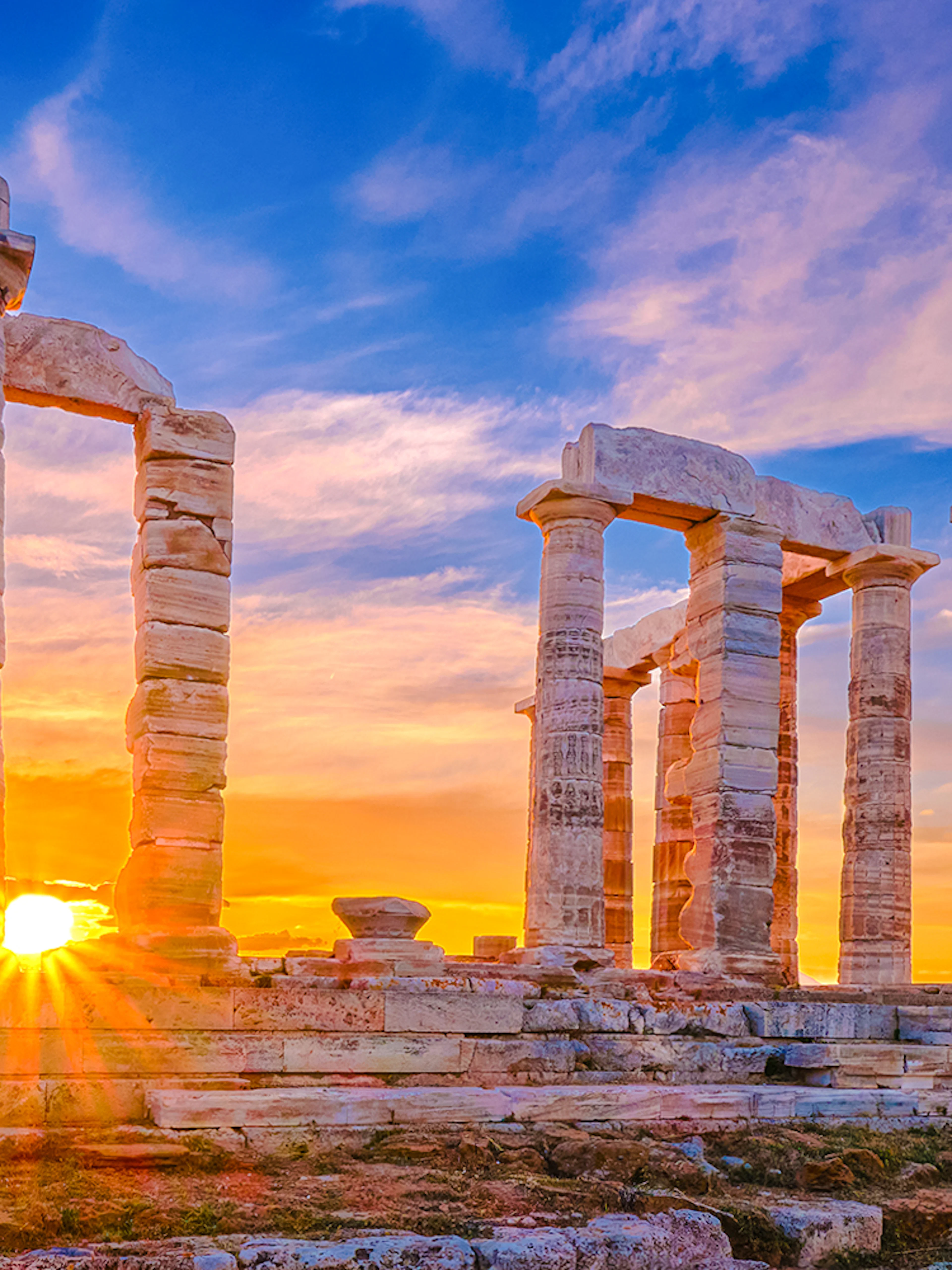 Sunset over ancient Temple of Poseidon ruins, Sounion, Greece.