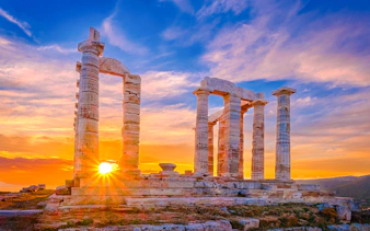 Sunset over ancient Temple of Poseidon ruins, Sounion, Greece.