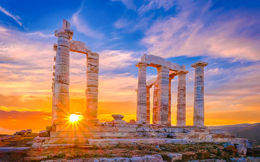 Sunset over ancient Temple of Poseidon ruins, Sounion, Greece.
