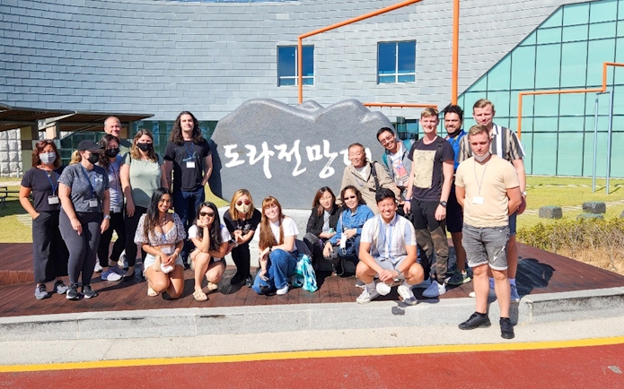 Group of tourists at the Korean Demilitarized Zone with a stone sign in the background.