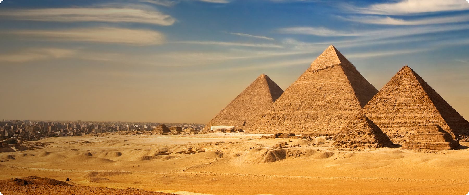 Pyramids of Giza with Cairo skyline in the background.