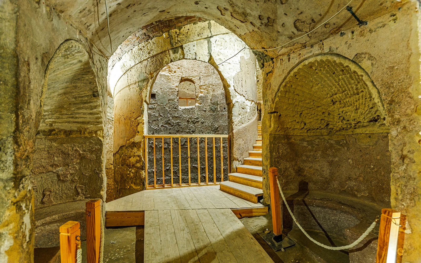 Ancient stone chamber with arched ceilings and wooden stairs in Cairo.