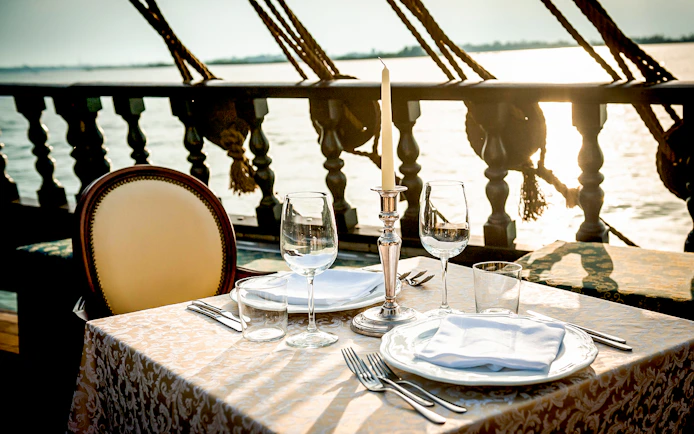 Dinner table set on a galleon cruise in Venice at sunset.