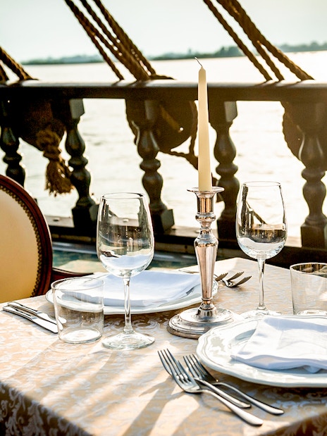 Dinner table set on a galleon cruise in Venice at sunset.