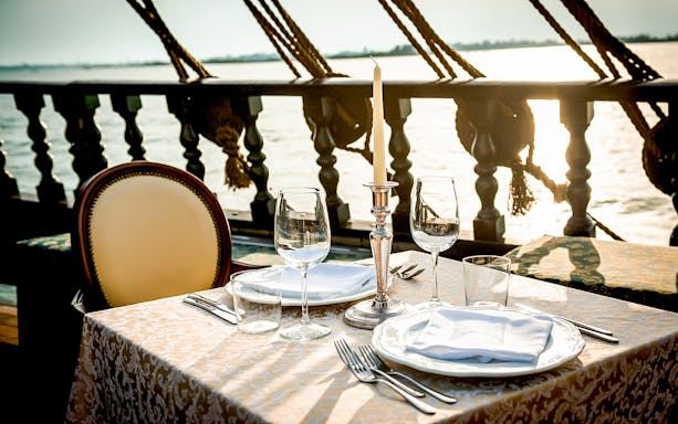 Dinner table set on a galleon cruise in Venice at sunset.