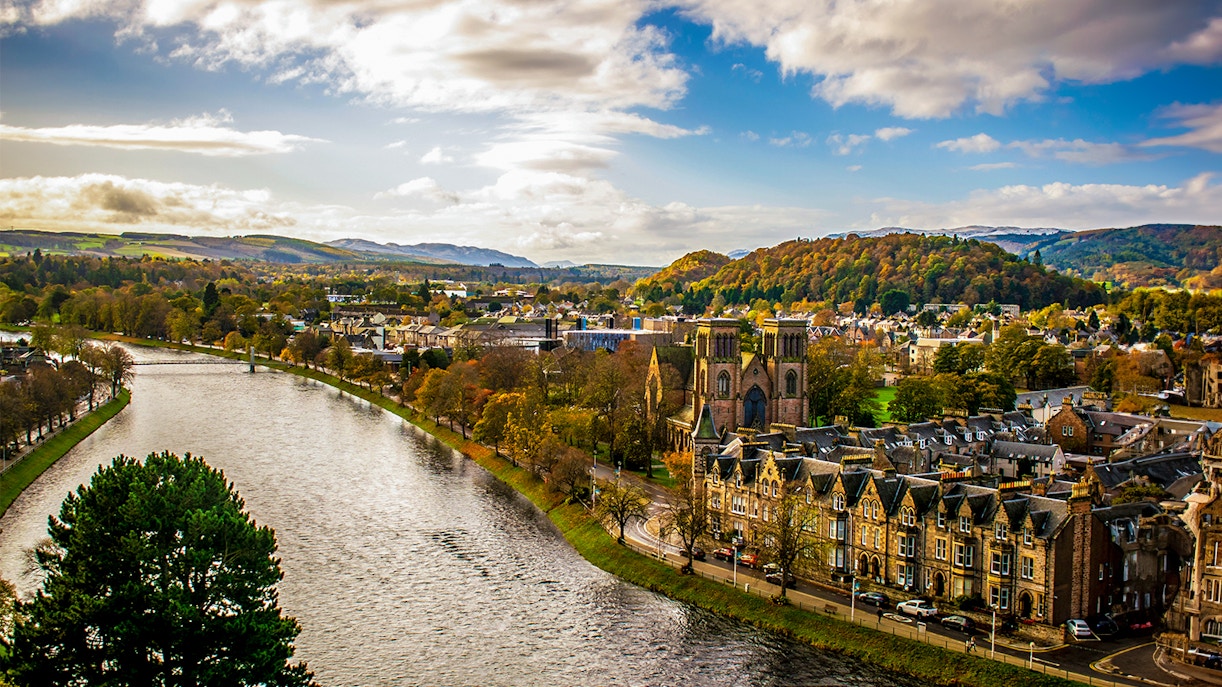 River Ness flowing through Inverness, Scotland with historic buildings and hills in the background.