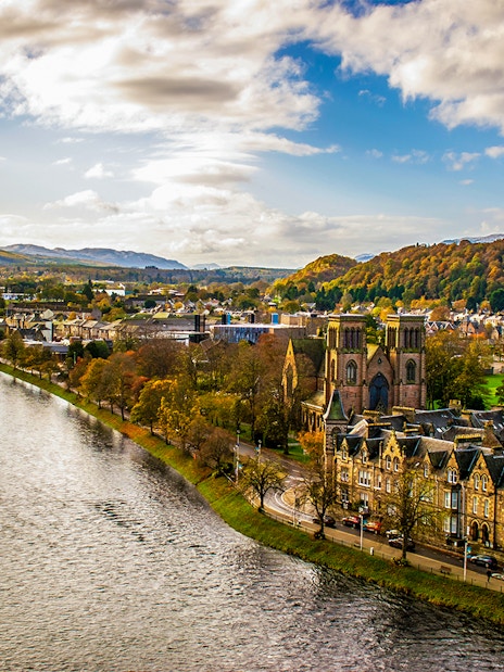 River Ness flowing through Inverness, Scotland with historic buildings and hills in the background.