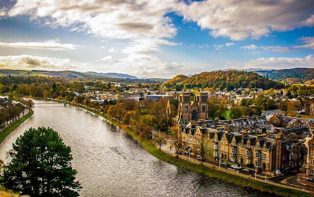 River Ness flowing through Inverness, Scotland with historic buildings and hills in the background.